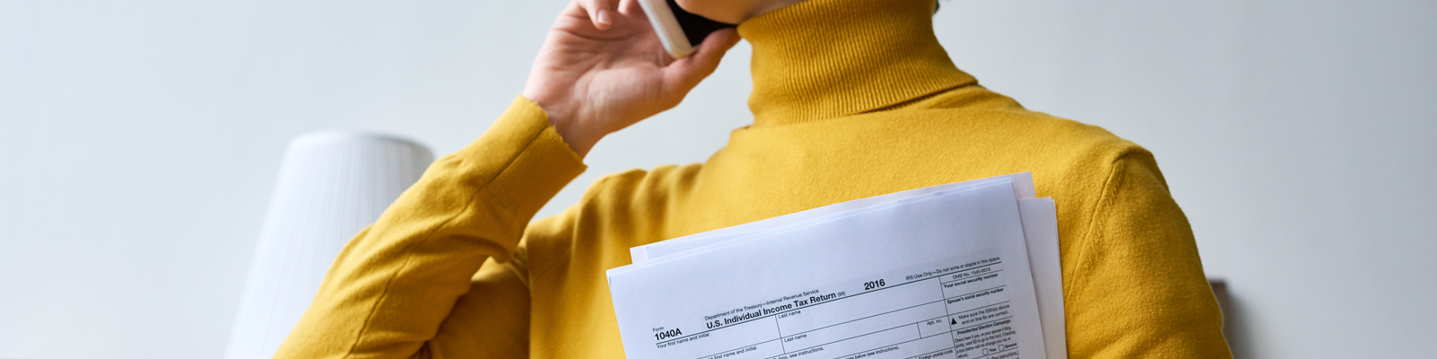 Woman on phone holding a stack of papers close to her chest